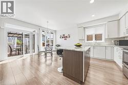 Open-concept kitchen and dining area featuring wood-finish flooring, white cabinetry, and a center island with a light-toned countertop - 