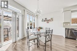 Open-concept dining area featuring wood-finish flooring, a contemporary chandelier, and extensive natural light from multiple windows - 