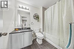 Bathroom featuring a vanity with dark countertop, undermount sink, and chrome faucet - 