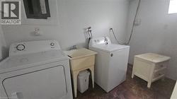 Utility room with a functional wash tub, durable tile flooring, and white walls - 