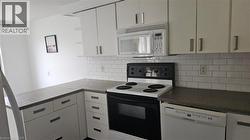 Kitchen featuring white cabinetry, gray countertops, and subway tile backsplash - 