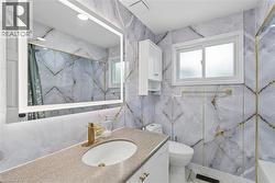 Bathroom featuring full-height marble-style wall paneling with gold-toned accents - 