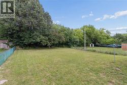 Expansive grassy yard area with mature perimeter trees providing natural screening - 