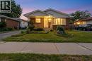 Brick and siding bungalow featuring a covered front porch with white railing, a concrete driveway, and a manicured lawn with decorative rock accents - 1259 Ernest Avenue, London, ON 
