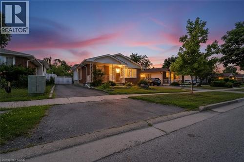 Bungalow-style residence featuring a brick and siding exterior, front porch, mature landscaping, and a paved driveway - 1259 Ernest Avenue, London, ON - Outdoor