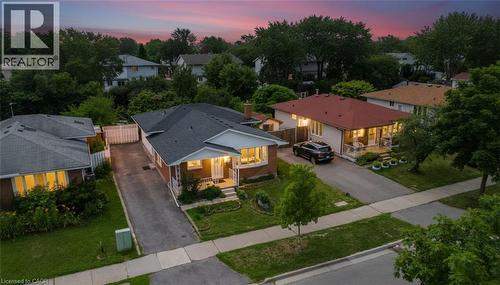 Brick exterior with a dark shingle roof, featuring a covered front porch, paved driveway, and manicured front lawn - 1259 Ernest Avenue, London, ON - Outdoor