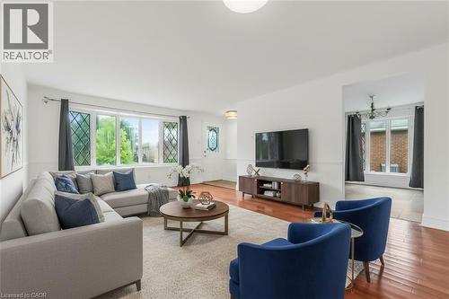 Bright living area featuring wood-finish flooring, white walls, and a large front window with decorative grilles - 1259 Ernest Avenue, London, ON - Indoor Photo Showing Living Room