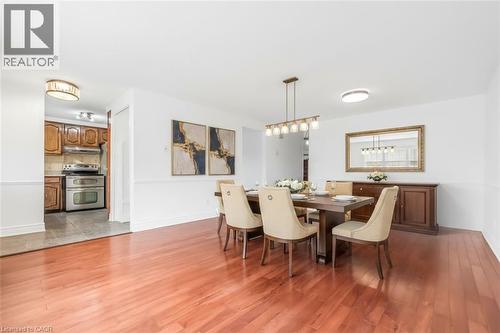 Dining area featuring wood-finish flooring, a linear chandelier, and wainscoting - 1259 Ernest Avenue, London, ON - Indoor Photo Showing Dining Room