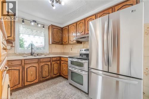Kitchen featuring wood cabinetry, light-toned countertops, and a tile backsplash - 1259 Ernest Avenue, London, ON - Indoor Photo Showing Kitchen With Double Sink