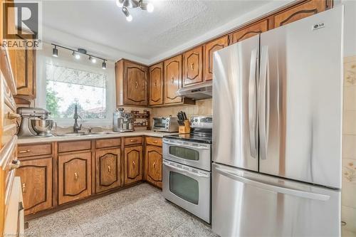 Kitchen featuring wood cabinetry, stainless steel French door refrigerator, stainless steel electric range with double oven, a single basin sink with a gooseneck faucet, and tile flooring - 1259 Ernest Avenue, London, ON - Indoor Photo Showing Kitchen