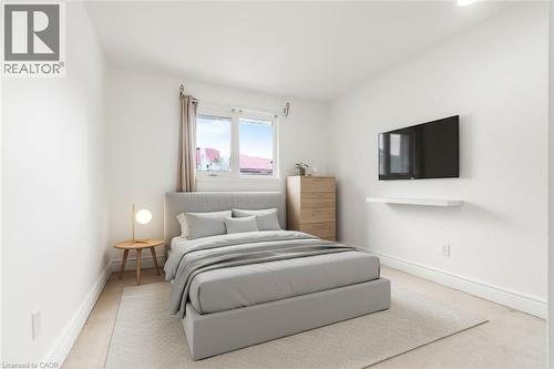 Bright bedroom featuring light wall paint, wood-finish flooring, and a large window with drapes - 1259 Ernest Avenue, London, ON - Indoor Photo Showing Bedroom