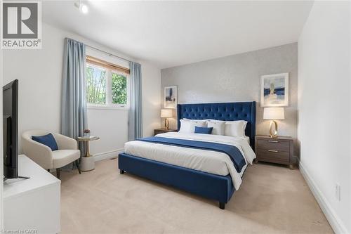 Carpeted bedroom featuring a large window with blinds and blue drapes, white painted walls, and a textured accent wall - 1259 Ernest Avenue, London, ON - Indoor Photo Showing Bedroom