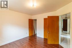 Spacious room featuring rich wood-finish flooring, white baseboards, and a semi-flush mount ceiling light fixture - 