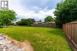 Expansive green lawn surrounded by mature trees and a wooden privacy fence - 