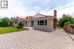 Exterior featuring light-toned brick and stone cladding, a red roof, and a red brick chimney - 