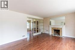 Hardwood-finish flooring throughout, featuring a traditional fireplace with a white mantel and brick surround - 