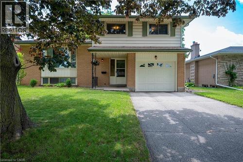 Brick and siding exterior featuring a covered entryway, a front-facing garage with decorative windows, and a paved driveway - 99 Lorraine Avenue, Kitchener, ON - Outdoor