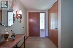 Entryway featuring a wood-panel door with a sidelight, light-toned tile flooring, and built-in wood cabinetry - 