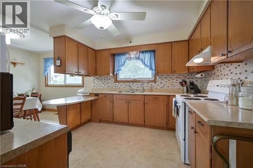 Kitchen featuring wood cabinetry, light-toned countertops, and a tile backsplash - 99 Lorraine Avenue, Kitchener, ON - Indoor Photo Showing Kitchen With Double Sink