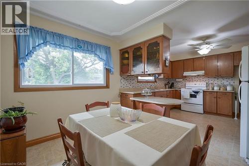 Functional kitchen and dining area featuring wood cabinetry, a built-in oven, and a ceiling fan with integrated lighting - 99 Lorraine Avenue, Kitchener, ON - Indoor