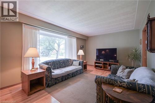 Spacious living area featuring light wood-finish flooring, a large picture window with sheer drapes, and a neutral wall color palette - 99 Lorraine Avenue, Kitchener, ON - Indoor Photo Showing Living Room