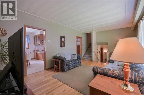 Hardwood flooring extends throughout this living space, featuring light green walls and a visible doorway to a kitchen area with wood cabinetry - 99 Lorraine Avenue, Kitchener, ON - Indoor