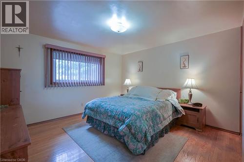 Bedroom featuring warm wood-finish flooring, a large window with vertical blinds, a flush mount ceiling light, and light-toned walls - 99 Lorraine Avenue, Kitchener, ON - Indoor Photo Showing Bedroom
