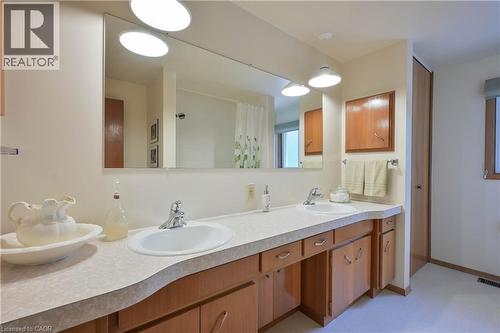 Double vanity with wood-finish cabinetry, integrated sinks, and neutral-toned countertops - 99 Lorraine Avenue, Kitchener, ON - Indoor Photo Showing Bathroom