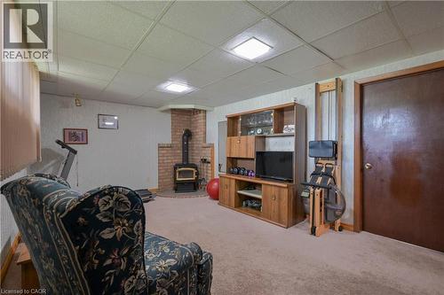 Lower level room featuring a brick corner fireplace with a wood-burning stove, carpet flooring, a drop ceiling, and recessed lighting - 99 Lorraine Avenue, Kitchener, ON - Indoor Photo Showing Other Room