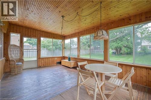 Sunroom featuring wood-finish paneling, wood-finish flooring, multiple windows, and a ceiling-mounted light fixture - 99 Lorraine Avenue, Kitchener, ON - Indoor Photo Showing Dining Room