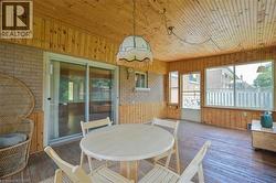 Enclosed patio featuring wood-finish walls and ceiling, large picture windows, and a sliding glass door - 