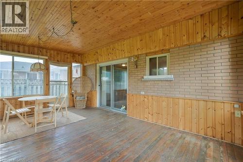 Enclosed porch featuring wood-panel walls and ceiling, brick exterior wall, sliding glass doors, and a suspended light fixture - 99 Lorraine Avenue, Kitchener, ON - Indoor