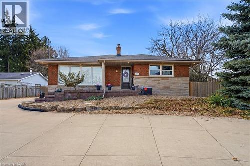 View of front facade with a chimney, stone siding, brick siding, and roof with shingles - 473 Mohawk Road W, Hamilton, ON 
