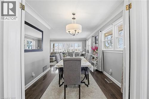 Dining room featuring dark wood-style flooring, plenty of natural light, and ornamental molding - 473 Mohawk Road W, Hamilton, ON 