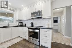 Kitchen with stainless steel appliances, white cabinets, and dark wood-style flooring - 