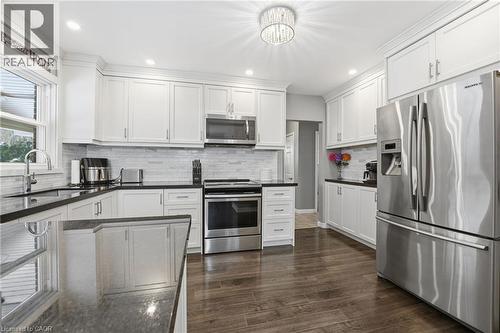 Kitchen featuring stainless steel appliances, white cabinets, dark wood-type flooring, recessed lighting, and tasteful backsplash - 473 Mohawk Road W, Hamilton, ON 