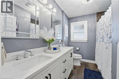 Full bathroom with double vanity, dark wood finished floors, and curtained shower - 473 Mohawk Road W, Hamilton, ON 
