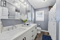 Full bathroom with double vanity, dark wood finished floors, and curtained shower - 