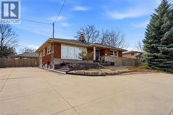 View of front facade featuring a chimney, stone siding, brick siding, and driveway - 