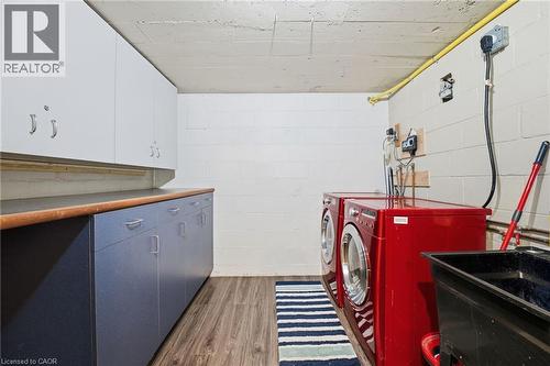 Laundry room featuring cabinet space, dark wood finished floors, and independent washer and dryer - 473 Mohawk Road W, Hamilton, ON 