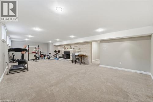 Workout area featuring light colored carpet and a fireplace with raised hearth - 473 Mohawk Road W, Hamilton, ON 