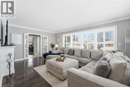 Living room with dark wood-type flooring, french doors, and ornamental molding - 473 Mohawk Road W, Hamilton, ON 
