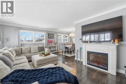 Living area featuring ornamental molding, dark wood-style floors, and a glass covered fireplace - 473 Mohawk Road W, Hamilton, ON 