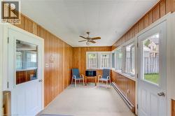 Sunroom featuring wood-paneled walls, white ceiling panels, and light-colored carpeting - 