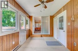 Sunroom featuring wood-panel walls and light-toned carpeting - 
