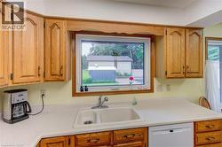 Kitchen featuring wood cabinetry, white countertops, a double basin sink with a chrome faucet, and a built-in dishwasher - 