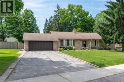 Ranch-style exterior with stone facade, attached two-car garage, asphalt driveway, and a front lawn with established landscaping - 