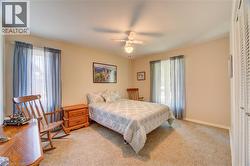 Carpeted room featuring a ceiling fan with integrated lighting, two windows, and a built-in louvered bi-fold closet - 