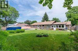 Expansive rear yard featuring a stone exterior, sunroom addition, mature trees, and a detached shed - 
