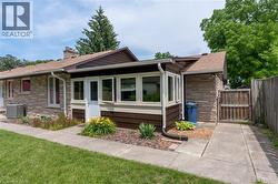 Stone veneer exterior featuring a prominent chimney and a sunroom with multiple windows - 